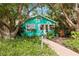 Charming teal bungalow nestled under lush trees, brick pathway leads to the front door at 5107 27Th S Ave, Gulfport, FL 33707