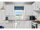 White kitchen with gray countertops, subway tile backsplash, and view to backyard at 5519 Blue Crush Bnd, Land O Lakes, FL 34638