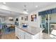 Kitchen with gray island, white cabinets, and view into living and dining area at 5519 Blue Crush Bnd, Land O Lakes, FL 34638
