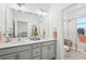 A main bathroom featuring dual sinks, a large mirror, gray cabinets, and a glass shower enclosure at 6324 Camino Dr, Apollo Beach, FL 33572