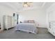 A bright main bedroom with a ceiling fan, tray ceiling, gray carpet, and white trim at 6324 Camino Dr, Apollo Beach, FL 33572