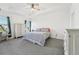 A bright main bedroom with a ceiling fan, tray ceiling, gray carpet, and white trim at 6324 Camino Dr, Apollo Beach, FL 33572