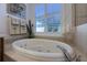 Oval jetted bathtub, shower, and tile flooring in this luxurious bathroom at 15731 Crystal Waters Dr, Wimauma, FL 33598
