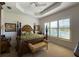 Main bedroom features a king-size bed and plantation shutters with water views at 15731 Crystal Waters Dr, Wimauma, FL 33598