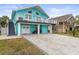 Two-story teal house with a large driveway and a golf cart at 17706 1St E St, Redington Shores, FL 33708