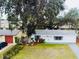 Single story home nestled amongst large trees, showcasing a well-manicured lawn at 1833 Knollwood Dr, Holiday, FL 34690