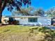 Newly renovated house with a white exterior, green lawn, and driveway at 1833 Knollwood Dr, Holiday, FL 34690