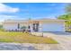 Tan house with a white garage door, landscaping, and a paved driveway at 2109 Elmwood Ct, Plant City, FL 33563