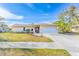 Tan house with a white garage door, landscaping, and a paved driveway at 2109 Elmwood Ct, Plant City, FL 33563