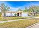 Tan house with a white garage door, landscaping, and a paved driveway at 2109 Elmwood Ct, Plant City, FL 33563