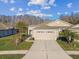Tan two-car garage home with a landscaped yard at 2932 Tanglewylde Dr, Land O Lakes, FL 34638