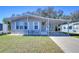 Gray mobile home with carport, landscaped lawn, and seating area at 4853 Blanco Dr, Zephyrhills, FL 33541