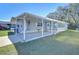 Gray mobile home with carport, landscaped lawn, and seating area at 4853 Blanco Dr, Zephyrhills, FL 33541