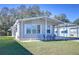 Gray mobile home with carport, landscaped lawn, and seating area at 4853 Blanco Dr, Zephyrhills, FL 33541
