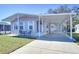 Gray mobile home with carport, landscaped lawn, and seating area at 4853 Blanco Dr, Zephyrhills, FL 33541