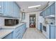 Open kitchen with light blue cabinets, white appliances, and view into dining area at 4853 Blanco Dr, Zephyrhills, FL 33541
