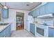Open kitchen with light blue cabinets, white appliances, and view into dining area at 4853 Blanco Dr, Zephyrhills, FL 33541