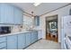 Open kitchen boasts light blue cabinets, white appliances, and a view to dining area at 4853 Blanco Dr, Zephyrhills, FL 33541