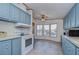 Bright kitchen with light blue cabinets, white appliances, and a large window at 4853 Blanco Dr, Zephyrhills, FL 33541