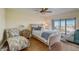 Bright bedroom with wood floors, a ceiling fan, a comfortable chair, and a view from the large sliding glass doors at 8711 Blind Pass Rd # 307A, St Pete Beach, FL 33706