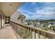 Balcony with a beautiful view of the neighborhood featuring palm trees, tennis courts, and sunny skies at 8711 Blind Pass Rd # 307A, St Pete Beach, FL 33706
