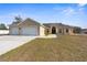 Tan house with two-car garage, arched entryway, and landscaping at 13254 Kitty Rd, Weeki Wachee, FL 34614