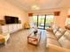 Living room with a large TV, comfy seating, and sliding glass doors at 10059 Crooked Creek Dr # 102, Venice, FL 34293
