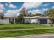 Updated mid-century modern home with a gray garage door and landscaped lawn at 1448 S Hercules Ave, Clearwater, FL 33764