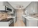 Modern kitchen with gray cabinets, stainless steel appliances, and tile backsplash at 14912 Brookridge Blvd, Brooksville, FL 34613