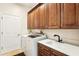 Laundry room with washer, dryer, white countertop, and wood cabinets at 18520 Oak Way Dr, Hudson, FL 34667