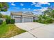Gray house with three-car garage, landscaping, and a large driveway at 6429 Seasound Dr, Apollo Beach, FL 33572