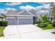 Gray house with three-car garage, landscaping, and a large driveway at 6429 Seasound Dr, Apollo Beach, FL 33572
