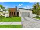 Modern home with stone and wood accents, gray garage door, and landscaped lawn at 1905 W Erna Dr, Tampa, FL 33603