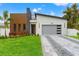Modern home with stone and wood accents, gray garage door, and landscaped lawn at 1905 W Erna Dr, Tampa, FL 33603