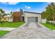 Modern home with stone and wood accents, gray garage door, and landscaped lawn at 1905 W Erna Dr, Tampa, FL 33603