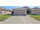 Front view of a beige house with a two-car garage and grassy area at 31447 Shaker Cir, Wesley Chapel, FL 33543