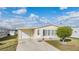 Single-wide manufactured home with attached garage and carport, featuring a well-manicured lawn at 37539 Gill Ave, Zephyrhills, FL 33541