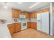 Bright kitchen featuring wood cabinets, white appliances, and laminate flooring at 37539 Gill Ave, Zephyrhills, FL 33541
