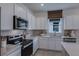 Modern kitchen with white cabinets, stainless steel appliances, and quartz countertops at 4177 Feldspar Ln, Spring Hill, FL 34609