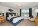Main bedroom with blue upholstered bed and lake view at 6659 Depue Dr, Wesley Chapel, FL 33545