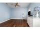 Light blue bedroom with hardwood floors, white dresser, and TV at 9244 Rhea Dr, Odessa, FL 33556