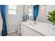 Clean bathroom with white cabinets, quartz countertop, and blue curtains at 32646 Rustic Rise Rd, San Antonio, FL 33576