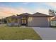 One-story house with neutral colors, a two-car garage, and a well-manicured lawn at 112 Sidney Ct, Rotonda West, FL 33947