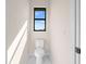 Small powder room with a toilet and a window, offering natural light at 112 Sidney Ct, Rotonda West, FL 33947