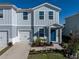 Two-story townhome with gray siding, two-car garage, and landscaped front yard at 3122 Victoria Inlet Dr, Holiday, FL 34691