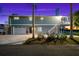 Two-story house with a garage, deck, and tropical landscaping at dusk at 555 Gulf Dr, Crystal Beach, FL 34681