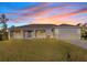 House exterior at dusk showcasing a beige exterior, gray roof, and landscaping at 7258 Bridgeport Ln, Englewood, FL 34224