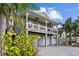 Elevated home with two-car garage, front porch, and tropical landscaping at 12116 Lagoon Ln, Treasure Island, FL 33706