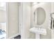 Small bathroom with pedestal sink and round mirror at 5287 Rushmere Ct, Palmetto, FL 34221
