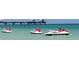 Three jet skis in the ocean near a pier at 660 Island Way # 1005, Clearwater Beach, FL 33767